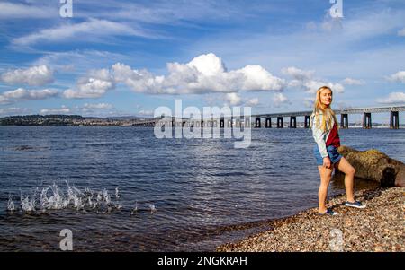 An einem wunderschönen Oktobertag in Wormit Beach, Fife, wirft Rhianna Martin Kiesel über ihren Kopf in den Fluss Tay, Schottland Stockfoto