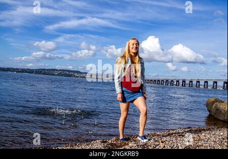 An einem wunderschönen Oktobertag in Wormit Beach, Fife, wirft Rhianna Martin Kiesel über ihren Kopf in den Fluss Tay, Schottland Stockfoto