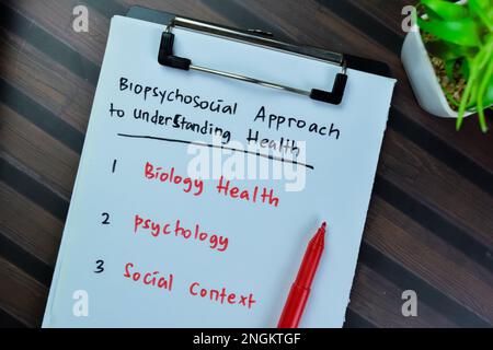 Konzept eines biopsychosozialen Ansatzes zum Verstehen von Gesundheit Schreiben Sie auf Unterlagen isoliert auf Holztisch. Stockfoto