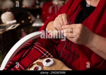 Großmutter näht eine weiche Eule im Weihnachtsgeschäft. Im Studio Stockfoto