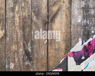 Bemalte Bretter, Zaun mit zerrissener Plakatwand. Farbe blättert von Gipswänden ab Stockfoto