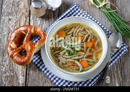 Bayrisches, schwäbisches und österreichisches Gericht - Leberspaetzle in einer Rindersuppe mit knuspriger Brezel Stockfoto