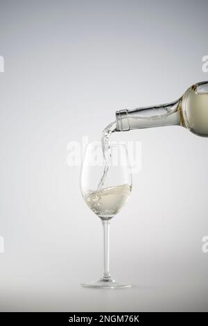 Weißwein wird in ein Weinglas gegossen Stockfoto