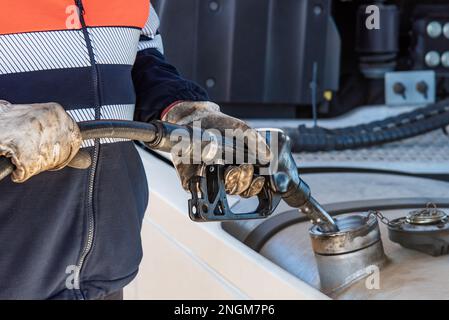 LKW-Fahrer mit einer Pumpdüse in den Händen, die den Kraftstofftank des Fahrzeugs füllt. Stockfoto