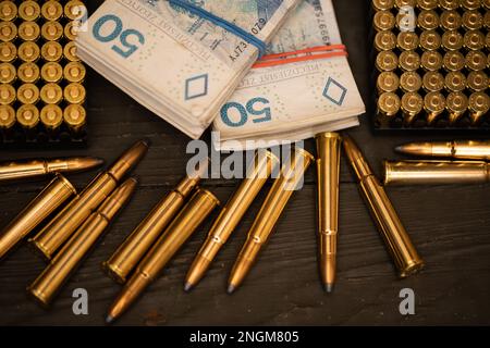 Scharfe Munition und ein Bündel Geld liegen auf einer militärischen Truhe. Stockfoto