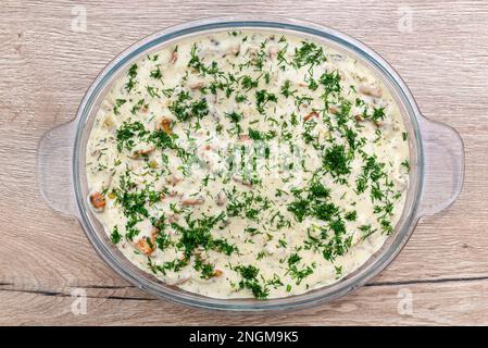 Gebackene Stücke Fischfilet in Pfifferlingscreme-Sauce in einer Glasschüssel. Stockfoto