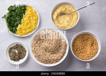 Zutaten für vegane Nussschnitzel mit Gemüse und Gemüse, Erdnüsse, Semmelbrösel, Kartoffelmischungen, gebratene Zwiebeln, Gehackte Petersilie und Gewürze Stockfoto