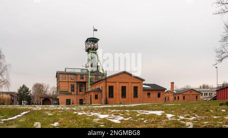 Zabrze, Schlesien, Polen - 11. Februar 2023: Gebäude der ehemaligen Mine „Concordia“, Wellenturm „Maciej“, durch ein großes Schwungrad gesehen. Stockfoto