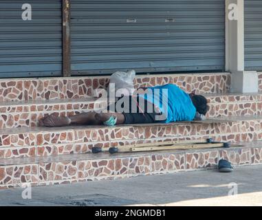 Behinderter - Invalide, liegt auf der Treppe vor dem geschlossenen Metalltor. Stockfoto