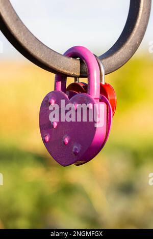 Das rosa, herzförmige Schloss hängt an der Brückenkette, der Hochzeitsstandard ist ein Symbol für ewige Liebe, Kopierraum Stockfoto