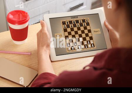 Frau, die online Schach auf einem Tablet spielt, drinnen, Nahaufnahme Stockfoto