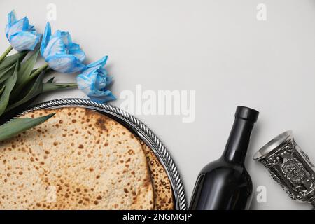 Schmackhafte Matzen, Wein und Tulpen auf hellgrauem Hintergrund, flach liegend mit Platz für Text. Pessach-Feier Stockfoto