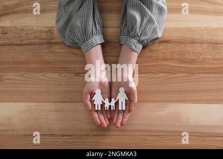 Frau hält eine Familienfigur am Holztisch, Draufsicht Stockfoto
