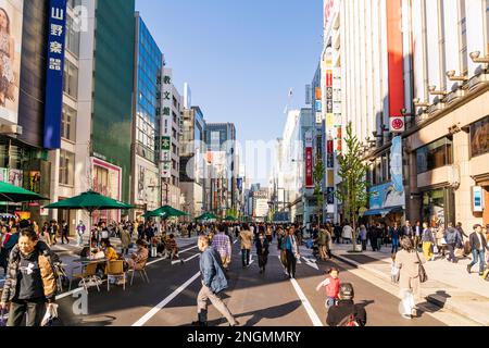 Luxushotels in der Nähe von Ginza, Tokyo's Shopping District. Die Leute an den Tischen sitzen, während andere entlang Chuo-dori am Wochenende, wenn es eine Fußgängerzone ist. Stockfoto