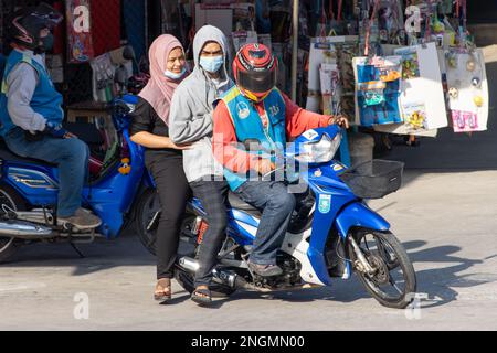 SAMUT PRAKAN, THAILAND, FEBRUAR 13 2023, Ein Motorradtaxi fährt einen Mann in einer Kapuze und eine Frau mit einem Hijab Stockfoto