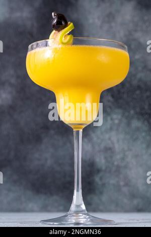 Glas gefrorenen Mango Daiquiri Cocktail garniert mit Limette und Maraschinokirsche Stockfoto