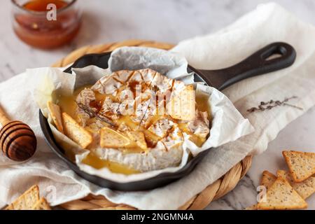 camembert weicher französischer Käse im Ofen mit Honig und Thymian, Seitenansicht Stockfoto