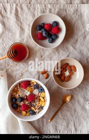 Frühstück mit Haferflocken, frischen Beeren, Mandeln und Honig auf dem Baumwolltisch, Draufsicht Stockfoto