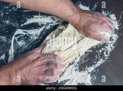 Nahaufnahme des Menschen Kneten Teig ein Holztisch, Lebensmittelzubereitung Konzept Stockfoto