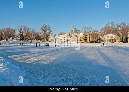 Jeunes qui patinent sur l'étang des Moulins gelé journée ensoleillée hiver. Kinder, die an einem sonnigen Tag auf einem gefrorenen Teich in Terrebonne skaten. Stockfoto