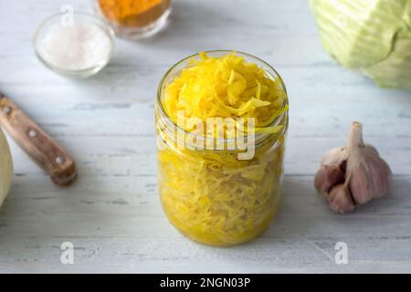 Hausgemachtes Sauerkraut mit Knoblauch, Zwiebeln und Kurkuma auf hellblauem Hintergrund. Gesunde fermentierte Lebensmittel, natürliche probiotische, vegane Lebensmittel. Draufsicht Stockfoto