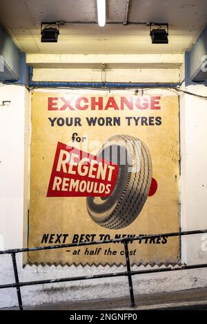 Restauriertes Geisterschild mit Werbung für Regent Remoulds Reifen auf dem Parkhaus der Poland Street im Londoner Stadtteil Soho Stockfoto