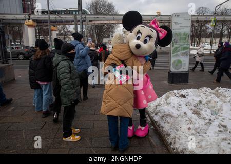 Moskau, Russland. 18. Februar 2023. Ein Mädchen umarmt eine Figur der Minnie Maus in einer Straße, die neu ist, am Haupteingang des VDNKh Exhibition Center in Moskau, Russland Stockfoto