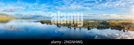 Malerische Bergketten spiegeln sich im ruhigen Wasser des Te Anau Sees und der Stadt Fiordland von Neuseeland - Tor zum Milford Sound. Stockfoto