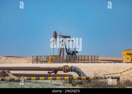 Pumpjack, auch bekannt als Ölpferd, nickender Esel, Ölpferd, Strahlpumpe hebt Rohöl in der Wüste Bahrain in Sakhir am Persischen Golf. Stockfoto