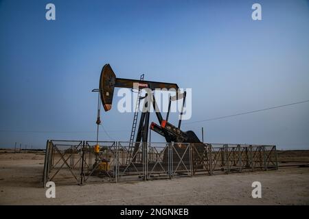 Pumpjack, auch bekannt als Ölpferd, nickender Esel, Ölpferd, Strahlpumpe hebt Rohöl in der Wüste Bahrain in Sakhir am Persischen Golf. Stockfoto