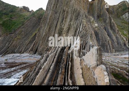 Blick auf steil geneigte Schichten von Flysch-geologischer Formation an der Atlantikküste bei Zumaia bei Ebbe, Baskenland, Spanien Stockfoto