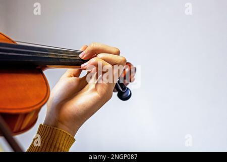 Trainiere die linke Hand an den Saiten auf der Geige des Schülers. Musikalische Erziehung Stockfoto