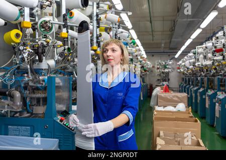 Grodno, Belarus - 22. November 2017: Eine Mitarbeiterin führt eine visuelle Qualitätskontrolle der Strumpfwaren im JLLC Conte Spa durch. Sogar hochpräzise Fertigung Stockfoto