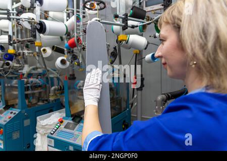 Grodno, Belarus - 22. November 2017: Eine Mitarbeiterin führt eine visuelle Qualitätskontrolle der Strumpfwaren im JLLC Conte Spa durch. Sogar hochpräzise Fertigung Stockfoto