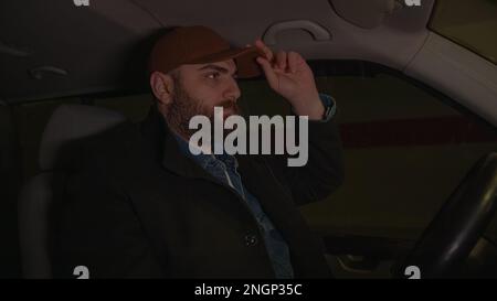 Indem er eine wichtige Sicherheitsregel verletzt, wie das Anlegen eines Sicherheitsgurts während der Fahrt, zeigt sich der kräftige, huttragende und bärtige junge Mann als Stockfoto