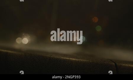 Fahrt durch eine herrliche Stadtlandschaft bei Nacht: Verschwommene Bokeh-Straßenbeleuchtung aus dem Vorderfenster eines fahrenden Autos, perfekt für urbanen Lebensstil, TR Stockfoto