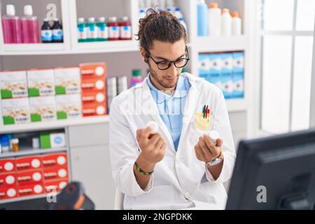 Junger hispanic-Mann Apotheker hält Pillen Flaschen in der Apotheke Stockfoto