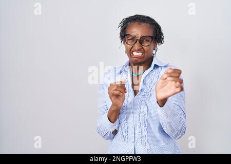 Afrikanische Frau mit Dreadlocks, die auf weißem Hintergrund steht, mit Brille, ekelhafter Ausdruck, verärgert und ängstlich, und ekelhaftes Gesicht macht, weil A Stockfoto