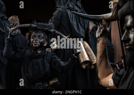 Luzon, Spanien. 18. Februar 2023. Ein kleiner Junge mit Gesicht, Armen und Händen, die mit Öl und Ruß bedeckt sind, mit Bullenhörnern und Kuhglocken, repräsentiert den Teufel während eines traditionellen Karnevalsfestes. Jedes Jahr richtet das kleine Dorf Luzon in Guadalajara ein Karnevalsfest mit dem Namen „Diablos y Mascaritas“ (Teufel und Masken) aus. Der Karneval stammt vermutlich aus der keltischen Zeit, obwohl der erste schriftliche Verweis, der Luzons Karneval dokumentiert, aus dem 14. Jahrhundert stammt. Kredit: Marcos del Mazo/Alamy Live News Stockfoto