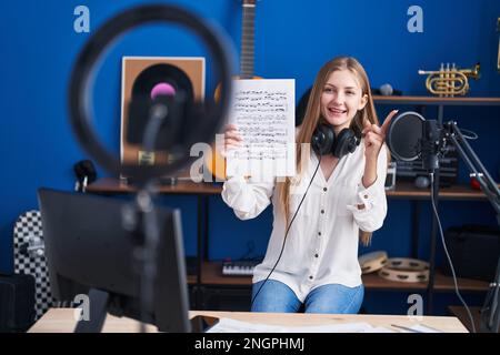 Junge kaukasische Frau macht Online-Musik-Tutorial zeigt Noten lächelnd glücklich zeigen mit Hand und Finger zur Seite Stockfoto