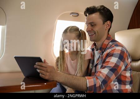 Vater mit Tochter, die Tablet im Flugzeug während des Fluges benutzt Stockfoto