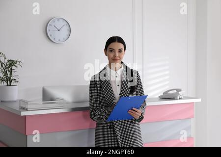 Rezeptionist mit Klemmbrett in der Nähe der Arbeitsfläche im Büro Stockfoto