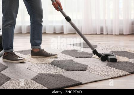 Mann, der zu Hause Teppich mit Staubsauger reinigt, Nahaufnahme Stockfoto