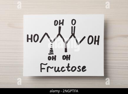 Papier mit dem Wort Fructose und gezeichnetem Schema auf weißem Holztisch, Draufsicht Stockfoto