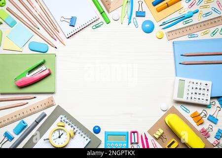 Rahmen mit verschiedenen Schreibwaren auf weißem Holzhintergrund, flach liegend. Platz für Text Stockfoto
