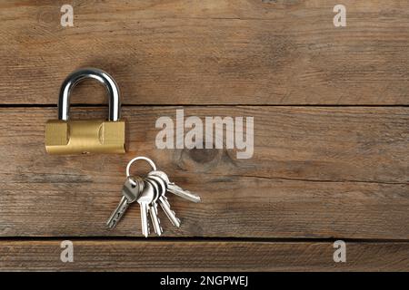 Modernes Vorhängeschloss mit Schlüsseln auf Holztisch, flach liegend. Platz für Text Stockfoto