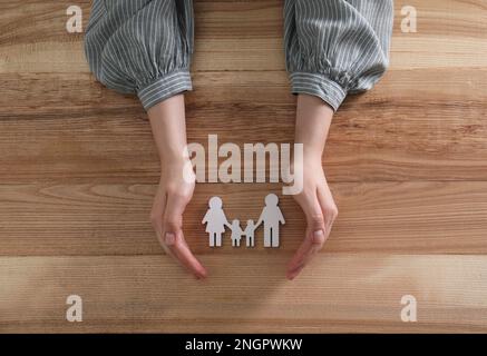 Frau mit Familienfigur am Holztisch, Draufsicht Stockfoto