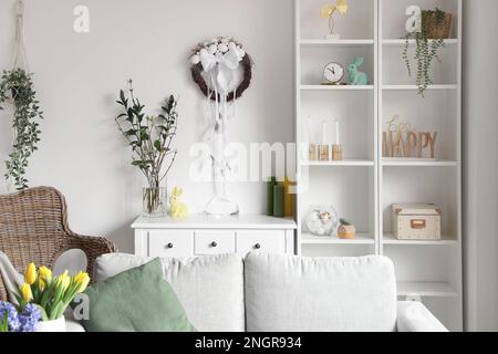Helles Wohnzimmer mit Osterkranz an der weißen Wand Stockfoto