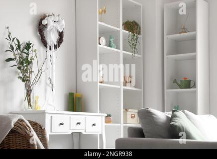 Der Osterkranz hängt an einer hellen Wand im Wohnzimmer Stockfoto