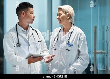 Arzt, Team und Ärzte sprechen Planung einer Operation mit einem Tablet in einem modernen Krankenhaus in Diskussion oder Forschung zusammen mit Mentor. Mann, Frau und Stockfoto
